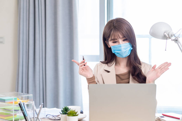 asian business woman is self quarantine - she use computer to join a video meeting with facial mask at home - 写真・画像
