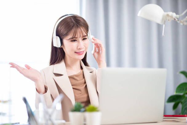 telework concept - Asian woman use computer and headphone microphone to join a video meeting at home - Фото, изображение