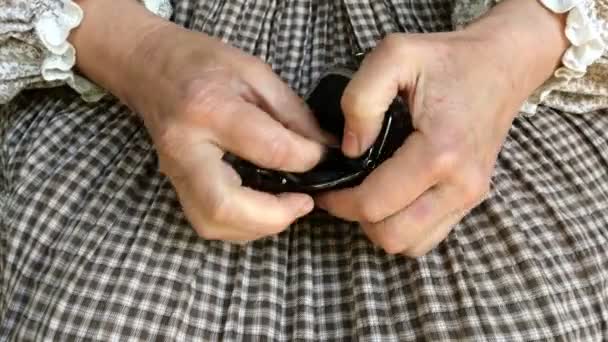 Kırsal giysili olgun bir kadının kırış kırış elleri siyah deri cüzdanı alır ve avucundaki farklı küçük paraları sayar. Yoksulluk ve finansal kriz kavramı. Kapat.. - Video, Çekim