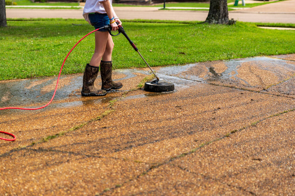 Vrouw druk wassen om schoon oprit van een huis - Foto, afbeelding