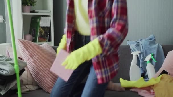 Exhausted woman in gloves sitting on sofa, relaxing after house cleaning work - Záběry, video