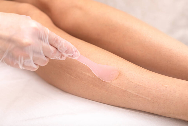 Laser hair removal on legs, hair removal by radiation. Spread a cooling cream on the skin before the procedure. Hands in gloves, closeup studio shot. Concept for articles about beauty services. - Photo, Image