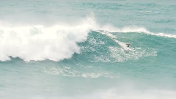 surfer in wetsuit en zwemvest rolt op reuzengolf in Portugal met instructeur, slow motion - Video