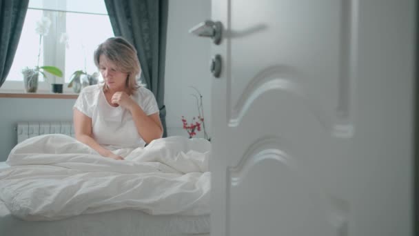 Female sits on bed, pain, pulls out a thermometer and watching the temperature - Filmagem, Vídeo