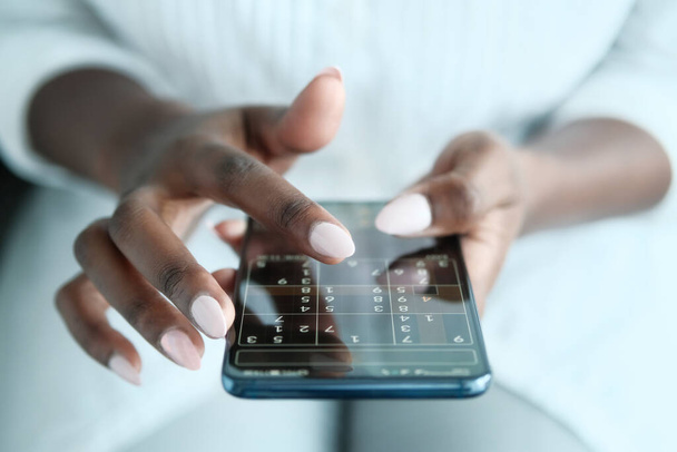 nero donna giocare sudoku su telefono per cervello formazione
 - Foto, immagini