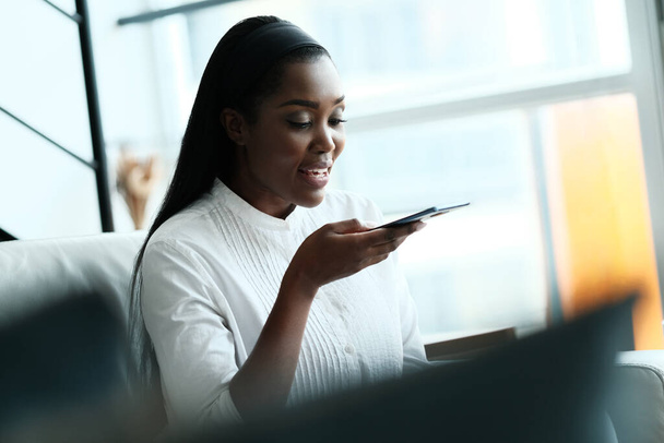 Черная женщина использует мобильный телефон для голосовой почты
 - Фото, изображение