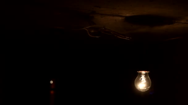 Lâmpada de tungstênio velho. A lâmpada incandescente com um filamento de tungstênio oscila no fio. Luz de uma lâmpada. Lâmpada close-up coberto com teias de aranha
. - Filmagem, Vídeo