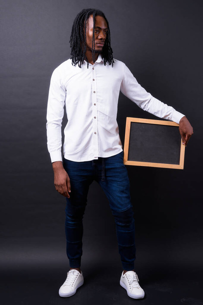 Зйомки молодого вродливого африканського бізнесмена з дредами на чорному тлі - Фото, зображення