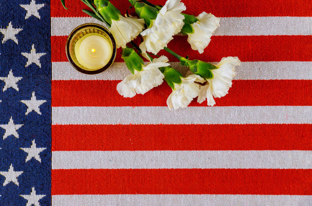 Bandera de América con flores blancas clavel y vela encendida. Vista superior
. - Foto, Imagen