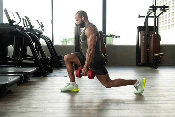 Strong Man In The Gym Exercising Legs With Dumbbells - Muscular Athletic Bodybuilder Fitness Model Exercise - Foto, Imagem
