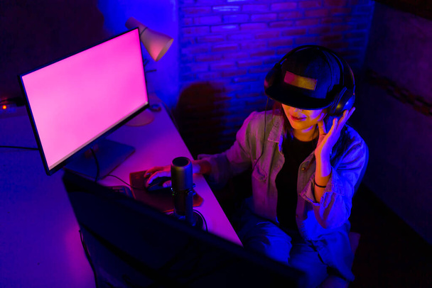 Uusi normaali iloinen aasialainen nainen käyttää kuulokkeita nauraa kannettavan videon stream konferenssi puhelu opettaa verkossa, Nuori aasialainen nainen vlogger ottaa live stream ja pelata online Video Game
 - Valokuva, kuva