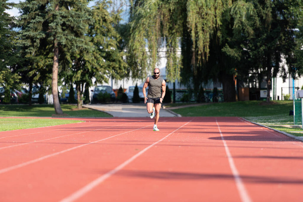 Sporty Man Running Fitness Workout on Track Exercising Outside - Photo, image