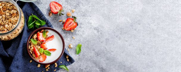 Ruokatausta. Aamiainen jogurtilla, myslillä tai myslillä ja mansikoita harmaalla betonipöydällä. Top view, kopioi tilaa, tasainen lay. Banner kuva verkkosivuilla, suunnittelu
 - Valokuva, kuva