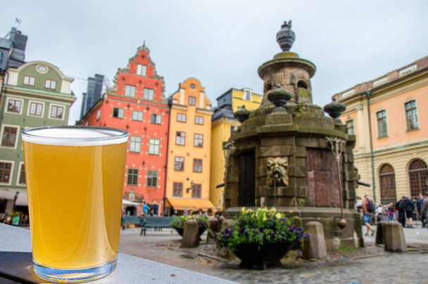 Ποτήρι μπύρας κατά της θέας του κέντρου της Στοκχόλμης στο Gamla stan, Σουηδία. Stortorget στην Παλιά Πόλη, την παλαιότερη πλατεία της Στοκχόλμης - Φωτογραφία, εικόνα