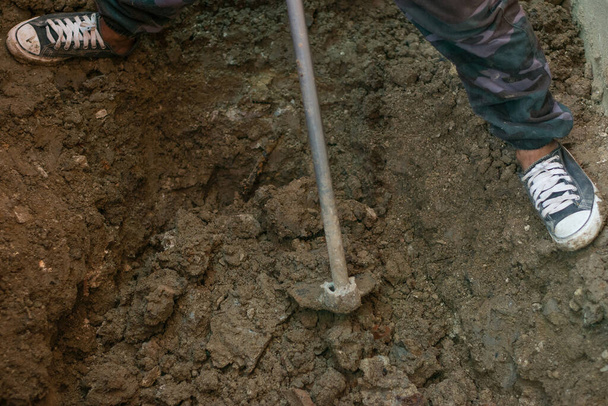 Ouvrier creuser un trou avec une houe sur le chantier de construction - Photo, image