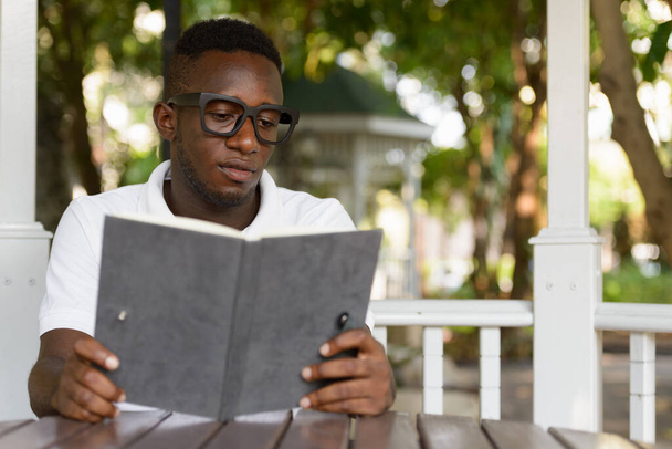 Portrait of young African nerd man as student with eyeglasses at the park outdoors - Fotó, kép