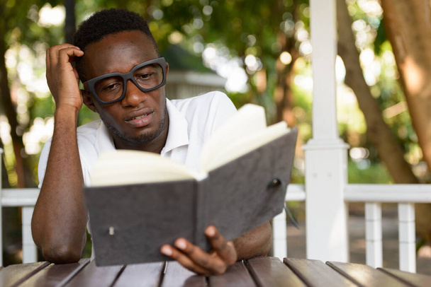 Portrait of young African nerd man as student with eyeglasses at the park outdoors - Foto, Imagem