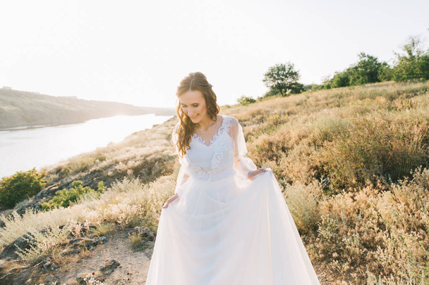Novia en un lujoso vestido de novia blanco en la naturaleza al atardecer
 - Foto, imagen
