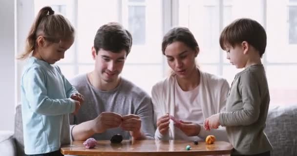 Young couple creating figures from plasticine with cute kids. - Séquence, vidéo
