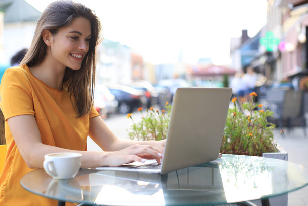 Улыбающаяся женщина использует ноутбук в кафе. Концепция предпринимателя, предпринимательницы, фрилансера
 - Фото, изображение