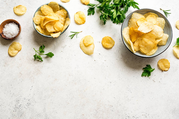 Oven baked  potato chips in bowls. Homemade crispy potato chips on white background, top view, copy space. - Φωτογραφία, εικόνα