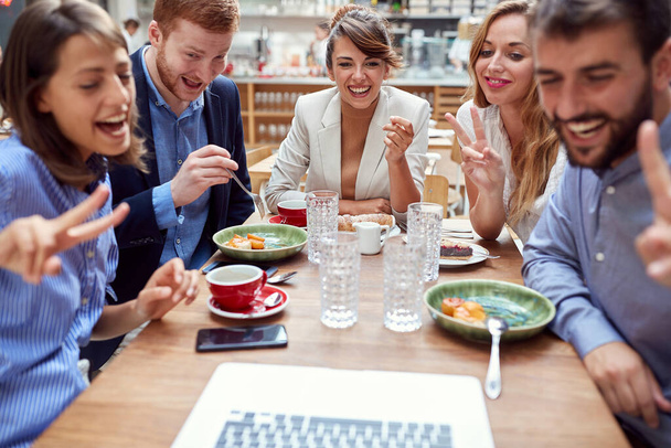 Gruppe junger Kaukasier bei einem Videotelefonat während des Mittagessens im Restaurant. Spaß, Technologie, Online, Internet, Freunde, Geschäftspartner, Kollegen  - Foto, Bild