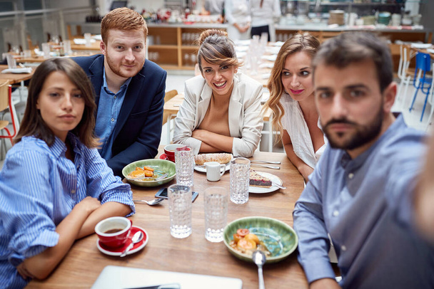 группа молодых кавказцев, делающих селфи за обедом в ресторане. весело, технологии, друзья, деловые партнеры, коллеги
  - Фото, изображение
