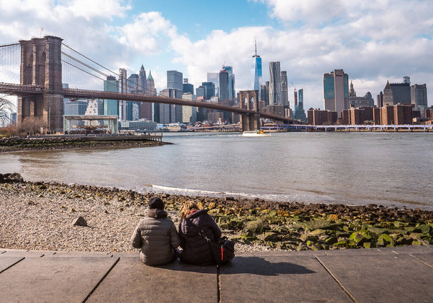 Junges Paar beobachtet im Winter die Brooklyn Bridge und Lower Manhattan - Foto, Bild