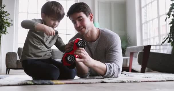 Focused small child boy learning fixing truck with father. - Video