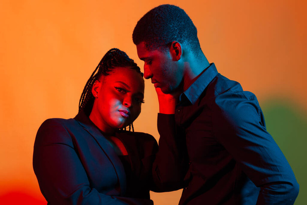 Тёмный неоновый портрет молодого африканского мужчины и женщины. Красный и синий свет
. - Фото, изображение