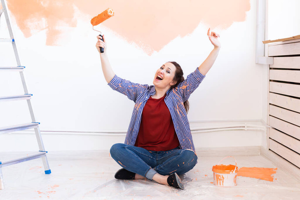Felice donna sorridente pittura parete interna della nuova casa. Ristrutturazione, ristrutturazione, riparazione di appartamenti e concetto di ristoro. - Foto, immagini