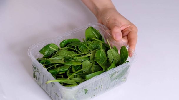 Frau verwendet Lebensmittelfolie zur Lagerung von Lebensmitteln auf einem weißen Tisch. Rolle transparenter Polyethylen-Lebensmittelfolie für Verpackungsprodukte. - Foto, Bild