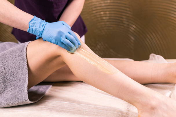 Hair removal at spa luxury shop. Women legs wax with sugaring. Hot sugar. - Photo, image
