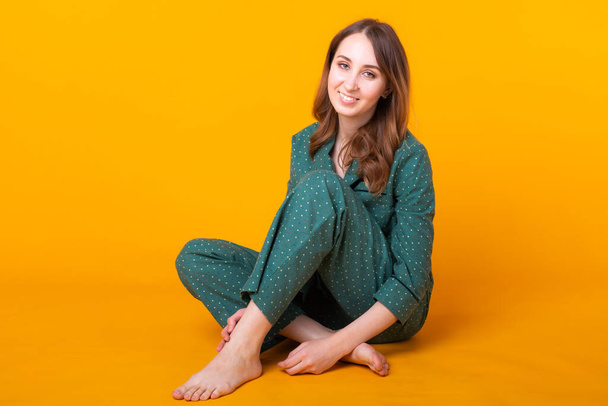 Young girl posing in pajamas on yellow background. Relax good mood, lifestyle and sleepwear concept. - Fotografie, Obrázek