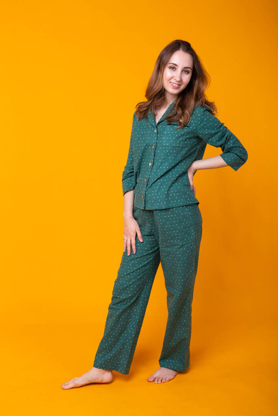 Young girl posing in pajamas on yellow background. Relax good mood, lifestyle and sleepwear concept. - Foto, Imagen