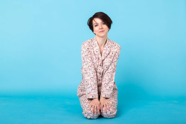 Young girl posing in pajamas on blue background. Relax good mood, lifestyle and sleepwear concept. - Zdjęcie, obraz