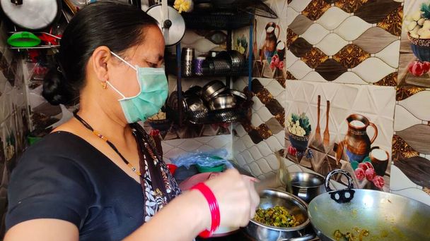Znepokojený indiánský dům manželka, žena, paní pod zámkem doma karanténa na sobě ochranné dýchání chirurgické obličejové masky proti chřipce a nové corona virus covid 19 pandemie, pracuje v kuchyni. - Fotografie, Obrázek