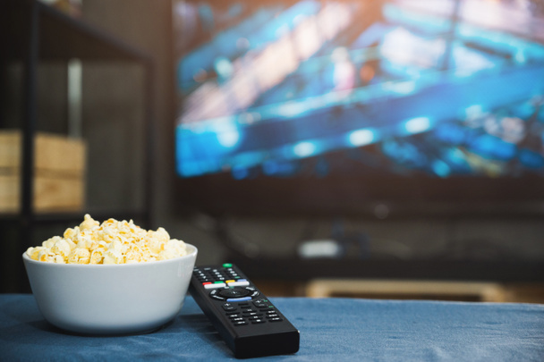 Popcorn en televisie afstandsbediening op tv scherm achtergrond. TV kijken ontspannen concept. - Foto, afbeelding