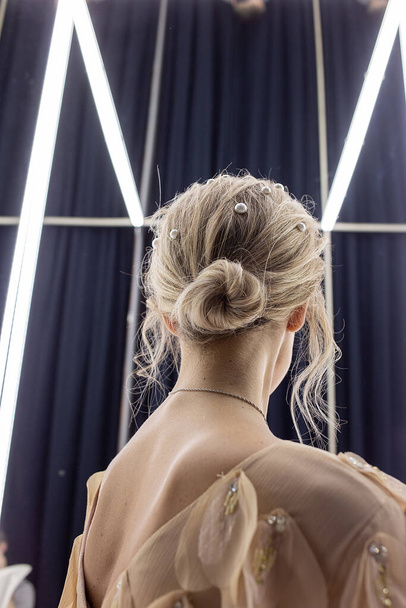 Блондинка стоит напротив зеркала, вид сзади. женщина с голыми лопатками
 - Фото, изображение