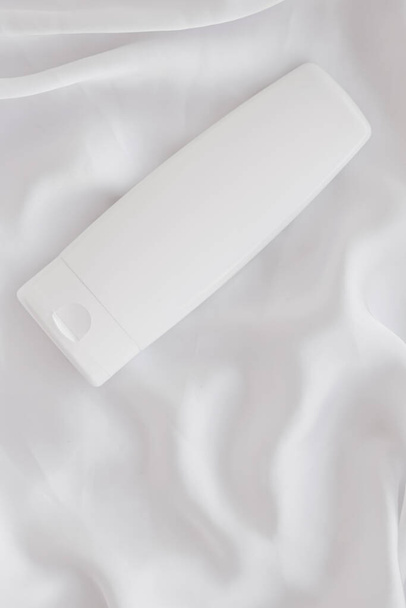 Prázdný štítek kosmetický obal láhev jako výrobek mokup na bílém hedvábí pozadí - Fotografie, Obrázek