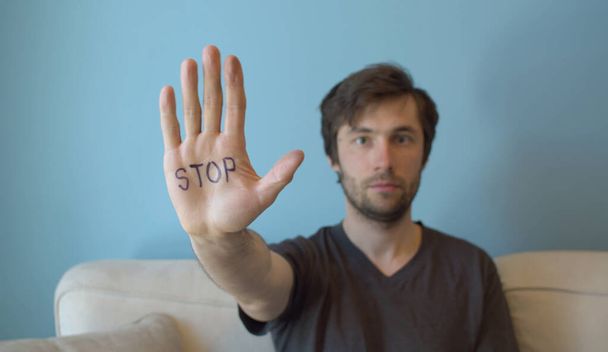 手に停止標識を示す若い男。セクシャルハラスメントに対する運動. - 写真・画像