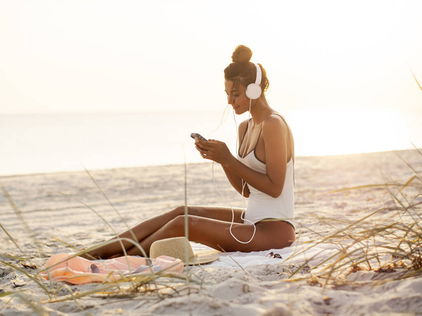 Woman in Bikini with a Smartphone and Headphones on the Beach - Фото, зображення