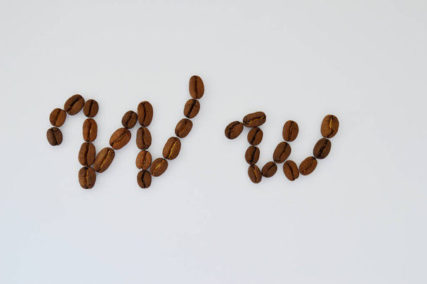 Uppercase letters w made of coffee beans on the white background. - Foto, imagen
