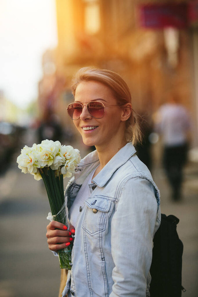Beautiful and young woman with a bouquet of daffodils - Foto, afbeelding