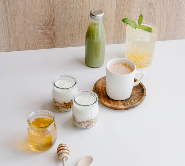 Zdravý snídaňový set s kávou, domácí jogurty s granolou, medem nebo agávovým sirupem a zeleným džusem.  - Fotografie, Obrázek