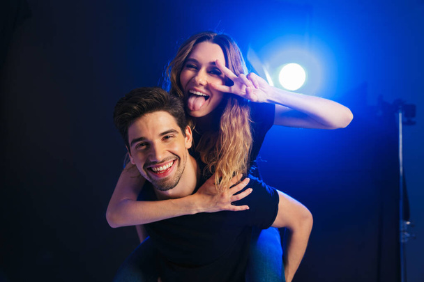 Image of a happy young amazing loving couple having fun resting in a night disco club on concert showing peace gesture. - Foto, imagen