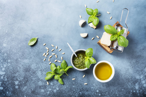 Fresh Italian pesto with basil, pine nuts, cheese and oil on the blue background. Top view image with a copy space - Foto, imagen