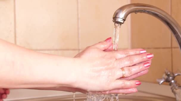 Το κορίτσι πλένει τα χέρια της με ζεστό νερό και σαπούνι μετά από μια βόλτα για να αποτρέψει τα μικρόβια ή τους ιούς από το να πάρει μέσα από βρώμικα χέρια. Πρόληψη και προστασία της υγείας και της ασφάλειας ζωής. - Πλάνα, βίντεο