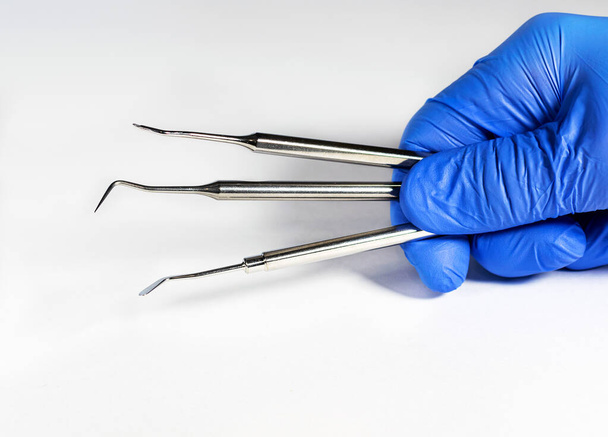 Sterile instruments in the dentist's hand in blue disposable latex gloves - Foto, imagen