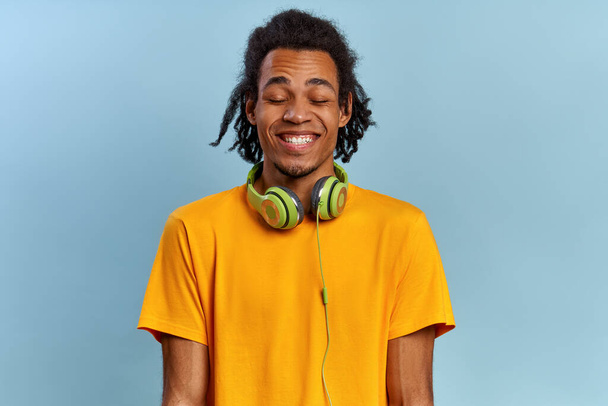 Cheerful smiling african-american guy with closed eyes from pleasure - Фото, изображение